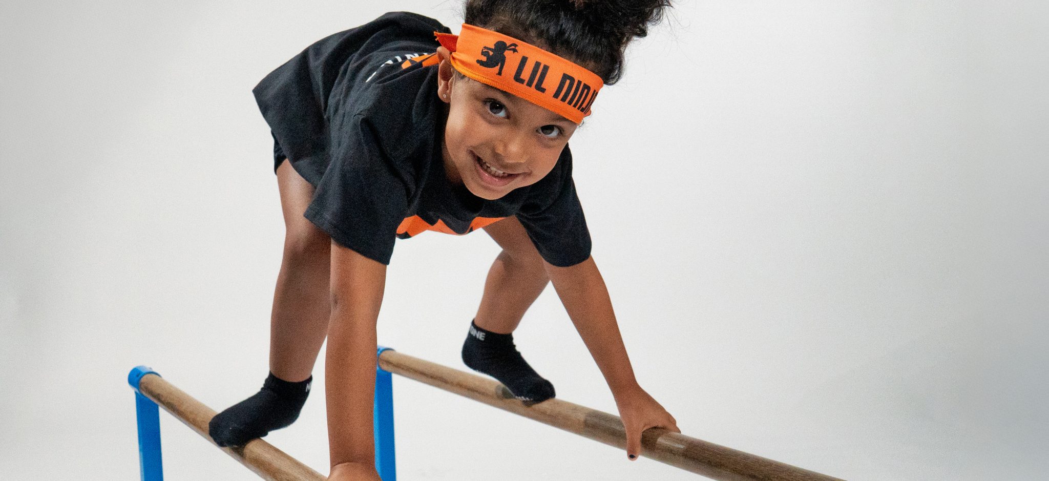 Lil ninja walking across parallel bars.